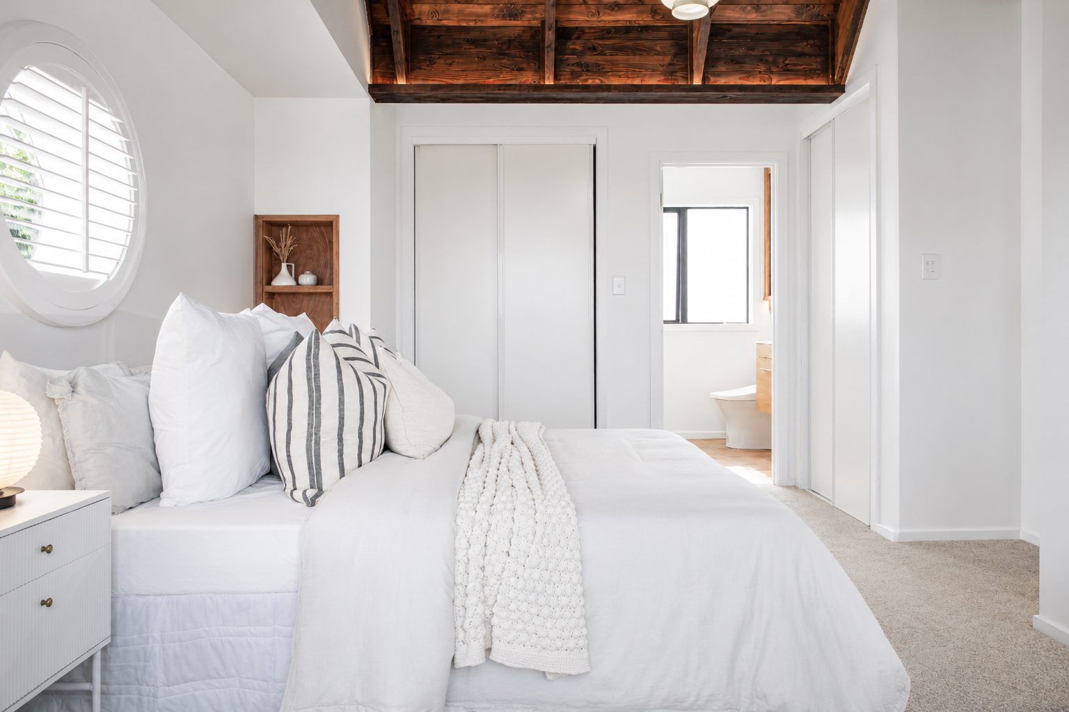 Guest bedroom with a round window and timber ceiling